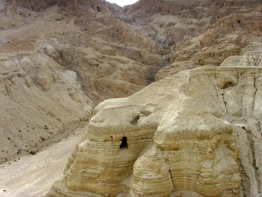 Foto: a entrada de uma gruta escavada num penhasco claro de Qumran
